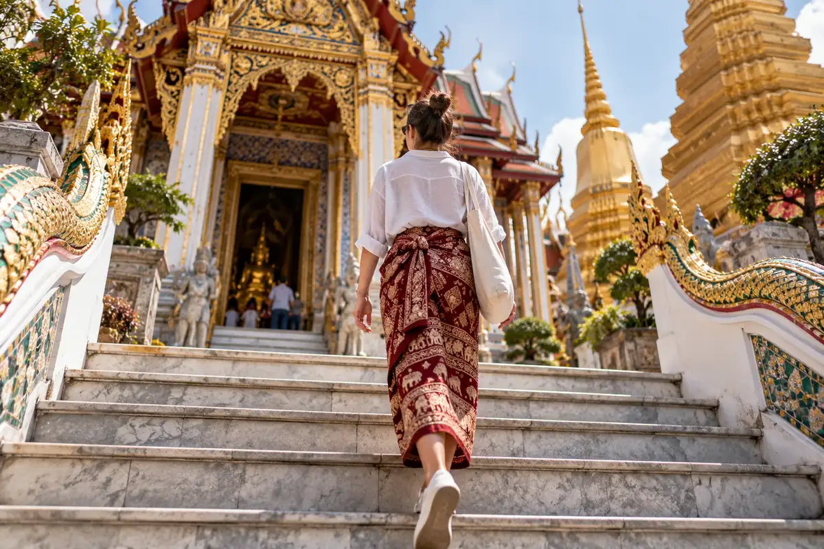 Voyageuse en tenue respectueuse montant les marches d'un temple, lors d'un voyage en Thaïlande